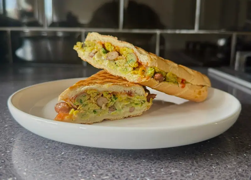 Chilli Onion Pinto Bean Egg Delight — a toasted panini cut open on a white plate