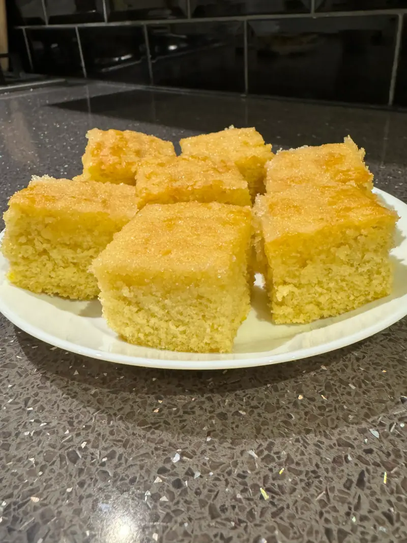 Squares of golden sponge traybake on a white plate